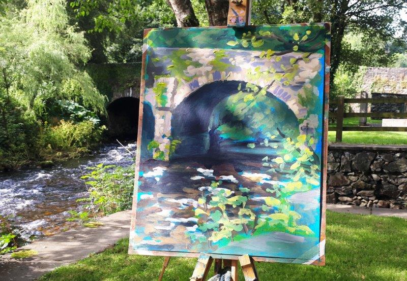 Photo of Rod Coyne's demo piece from the June Painting Workshop in 2019. It depicts a painting of the bridge on the easel with the stone bridge in the background.
